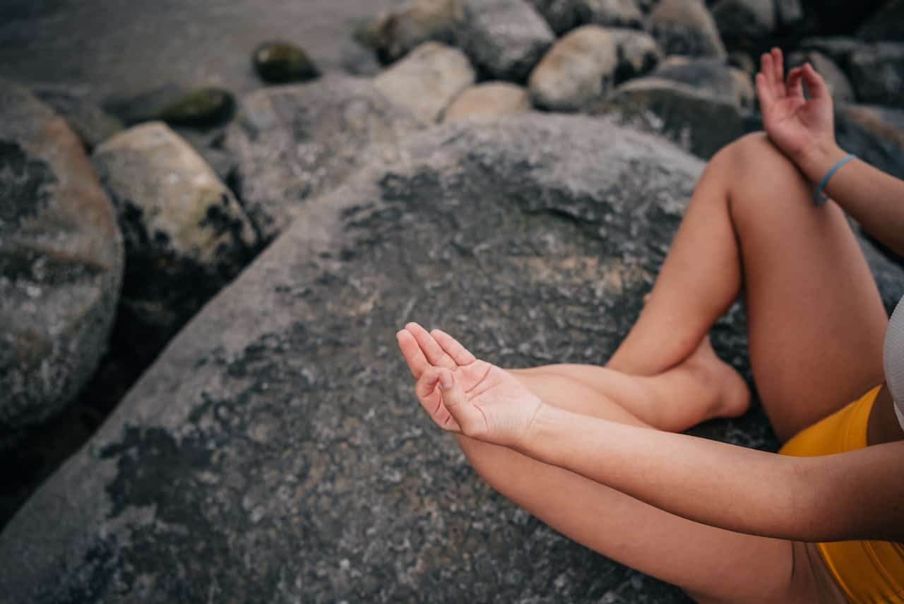 Nainen meditoimassa kiven päällä